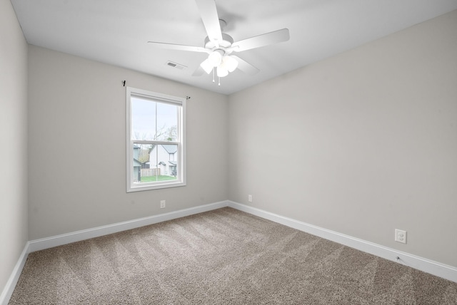 carpeted empty room with baseboards, visible vents, and a ceiling fan