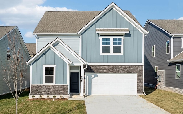 view of front facade featuring an attached garage, board and batten siding, stone siding, driveway, and a front lawn