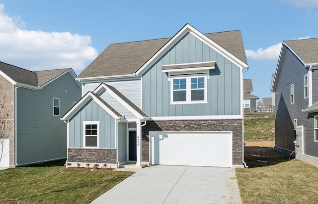 view of front of house with an attached garage, stone siding, driveway, a front lawn, and board and batten siding