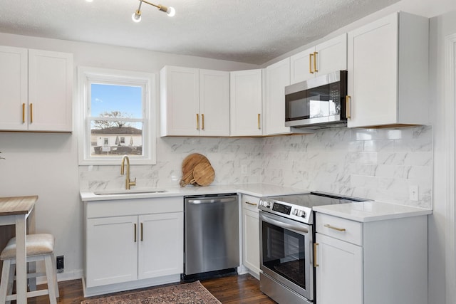 kitchen featuring appliances with stainless steel finishes, light countertops, a sink, and backsplash