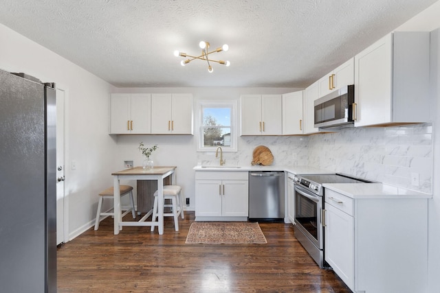 kitchen featuring stainless steel appliances, dark wood finished floors, white cabinets, and a sink