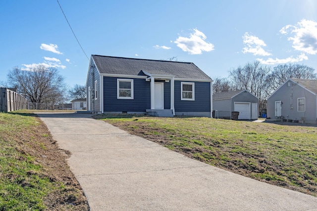 bungalow-style house featuring a detached garage, fence, a front lawn, and an outbuilding