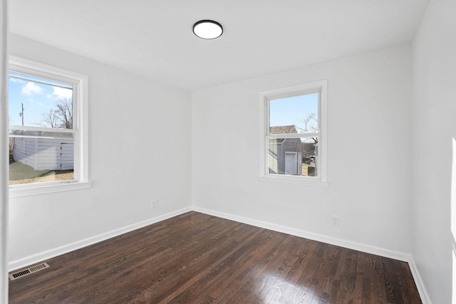 spare room with dark wood-style floors, baseboards, and visible vents