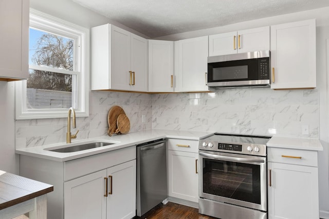 kitchen with backsplash, stainless steel appliances, a sink, and light countertops