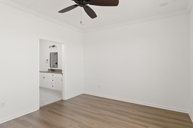 spare room featuring ceiling fan, light wood-style flooring, a sink, baseboards, and ornamental molding