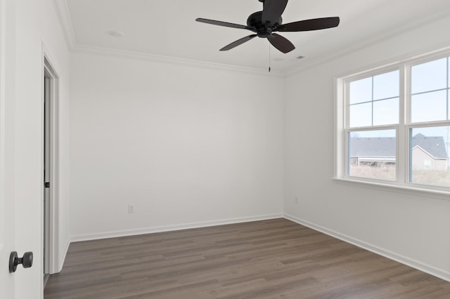 spare room with baseboards, wood finished floors, and crown molding