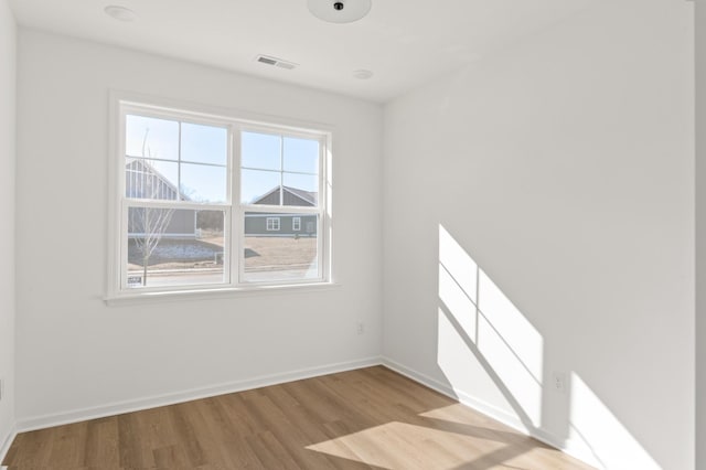 spare room with visible vents, baseboards, and wood finished floors