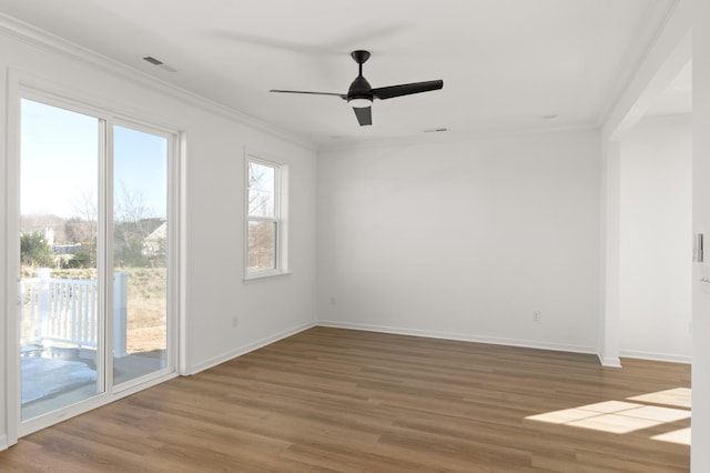 spare room featuring visible vents, crown molding, baseboards, and wood finished floors