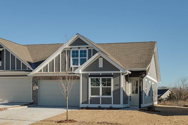 view of front of property featuring driveway, roof with shingles, board and batten siding, and brick siding