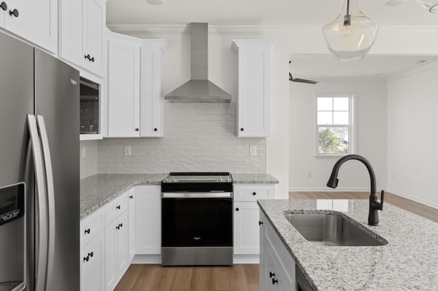 kitchen with wood finished floors, stainless steel appliances, wall chimney range hood, and a sink