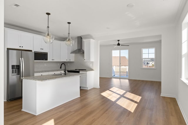 kitchen with stainless steel fridge with ice dispenser, a sink, wall chimney range hood, black microwave, and backsplash