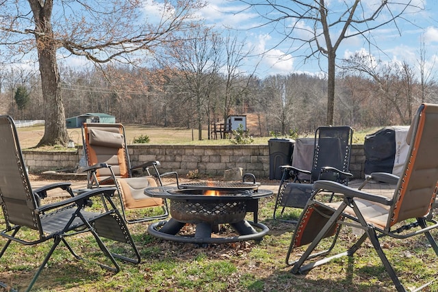 view of yard with an outdoor fire pit and a wooded view