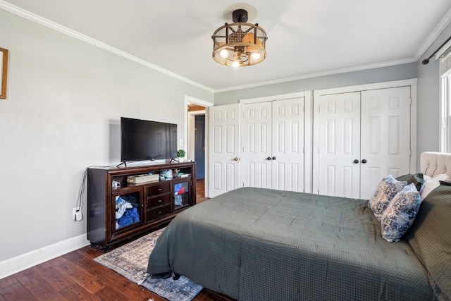 bedroom with baseboards, ornamental molding, two closets, and wood finished floors