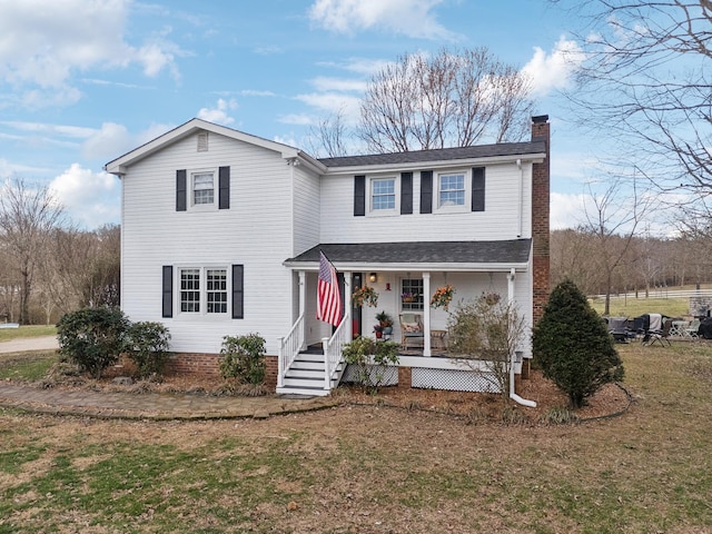 traditional home featuring a chimney, a front lawn, and a porch