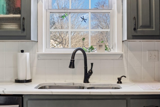 interior details featuring light stone counters, gray cabinets, and a sink