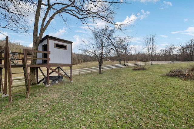 view of yard with fence, an outbuilding, and a rural view