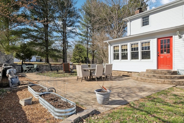 view of patio / terrace with entry steps, a garden, and outdoor dining space