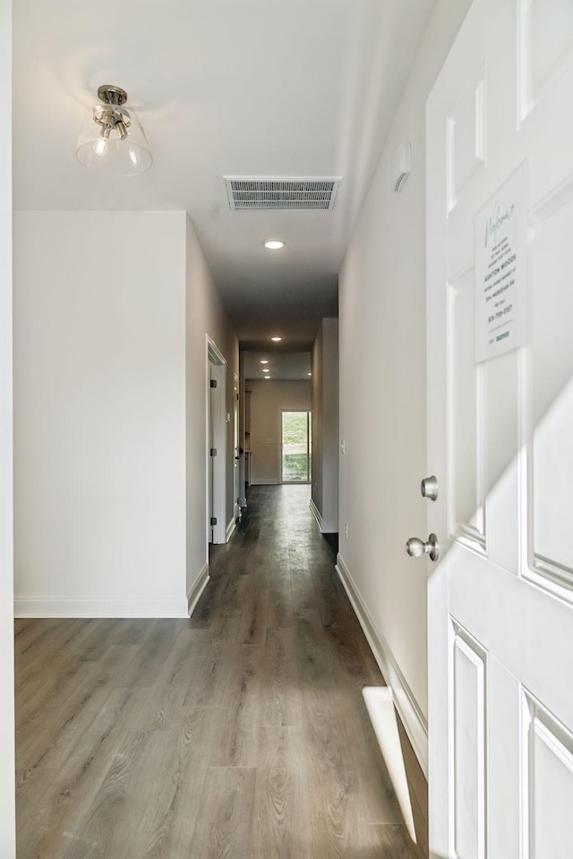 hallway with baseboards, visible vents, and wood finished floors