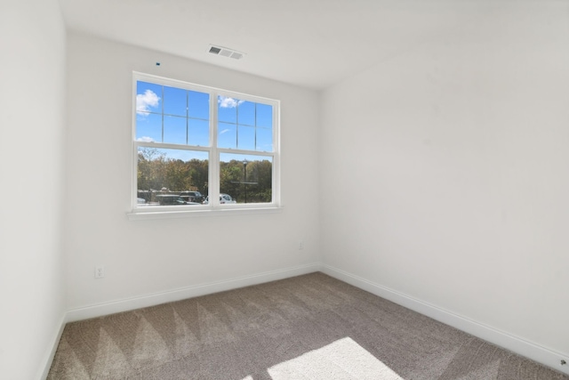 spare room featuring carpet floors, visible vents, and baseboards