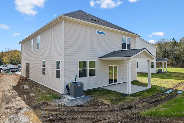 rear view of property featuring a patio area, central AC, a lawn, and roof with shingles