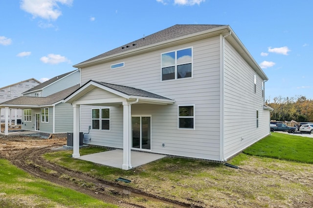 back of house with roof with shingles, a patio area, a yard, and central air condition unit