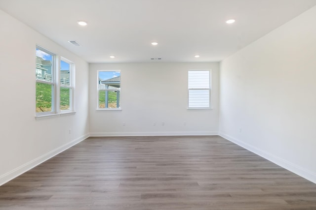 empty room featuring plenty of natural light, wood finished floors, and recessed lighting