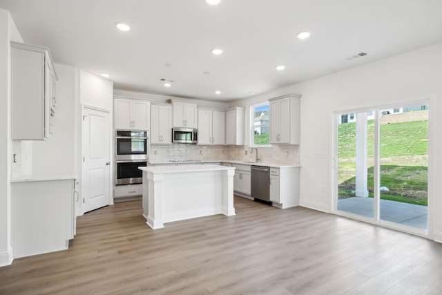 kitchen featuring light wood-type flooring, visible vents, appliances with stainless steel finishes, and decorative backsplash