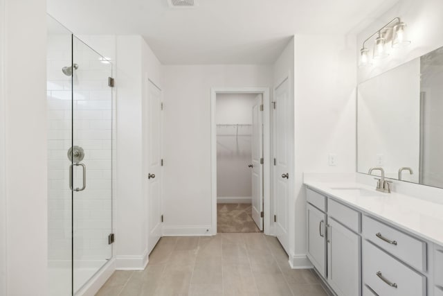 full bath with visible vents, a shower stall, vanity, and a spacious closet