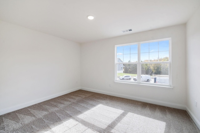 unfurnished room featuring carpet, visible vents, and baseboards