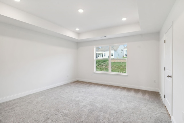 empty room featuring carpet, baseboards, a raised ceiling, and recessed lighting