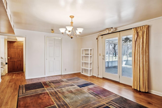 interior space featuring a notable chandelier, wood finished floors, baseboards, and ornamental molding