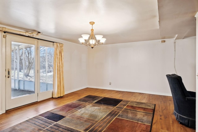 interior space featuring baseboards, crown molding, an inviting chandelier, and wood finished floors