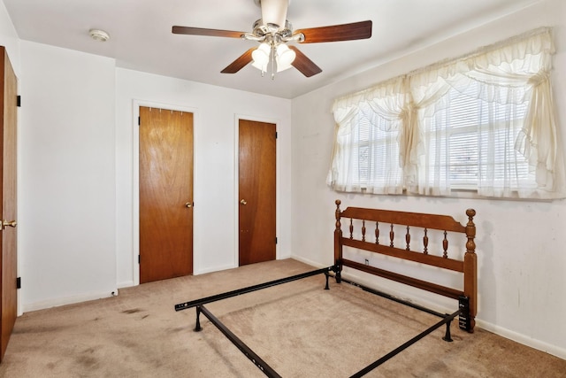 carpeted bedroom with ceiling fan, baseboards, and multiple closets