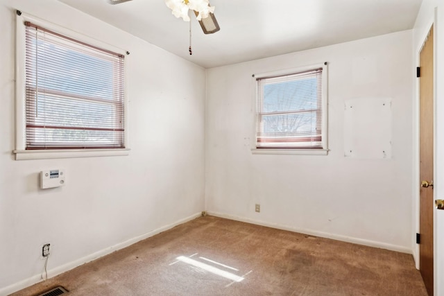 carpeted empty room with plenty of natural light, a ceiling fan, and baseboards