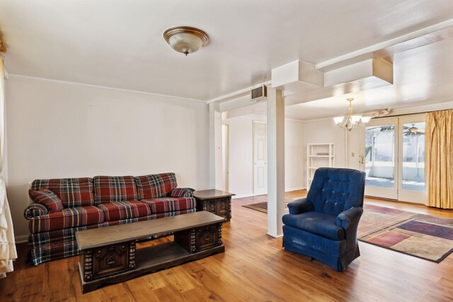 living area with ornamental molding, wood finished floors, visible vents, and a chandelier