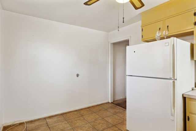 kitchen featuring baseboards, light countertops, light tile patterned floors, freestanding refrigerator, and a ceiling fan