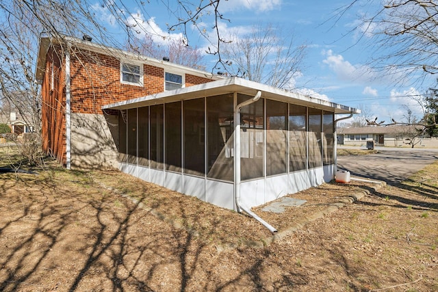 rear view of property with brick siding and a sunroom