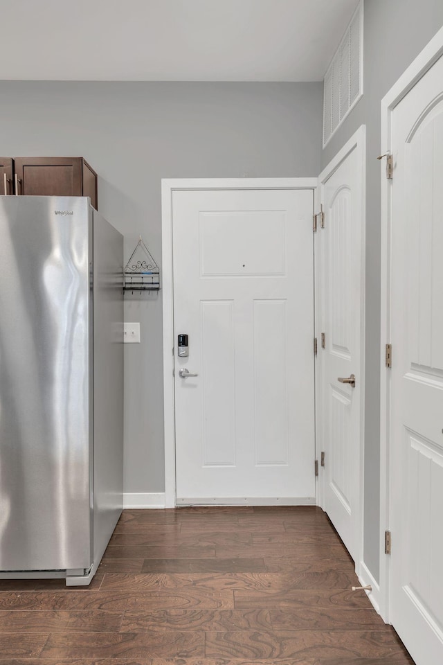 interior space with visible vents, dark wood-style floors, freestanding refrigerator, and baseboards