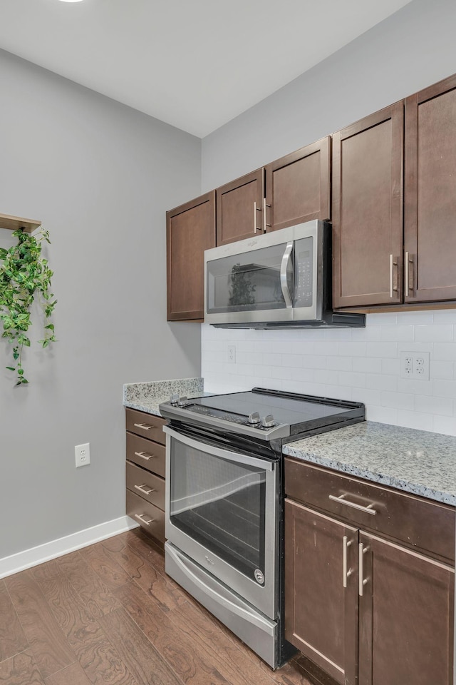 kitchen featuring dark brown cabinetry, dark wood-type flooring, stainless steel appliances, and decorative backsplash