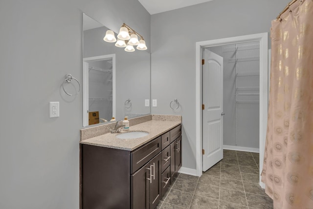 bathroom with a spacious closet, tile patterned floors, vanity, and baseboards