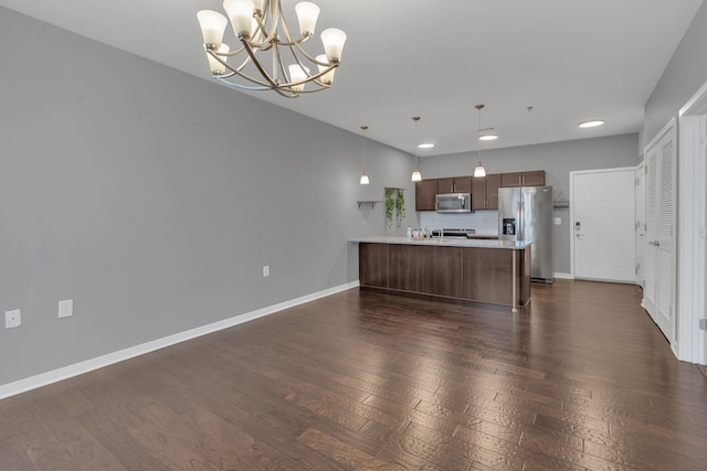 kitchen with stainless steel appliances, a peninsula, light countertops, and baseboards