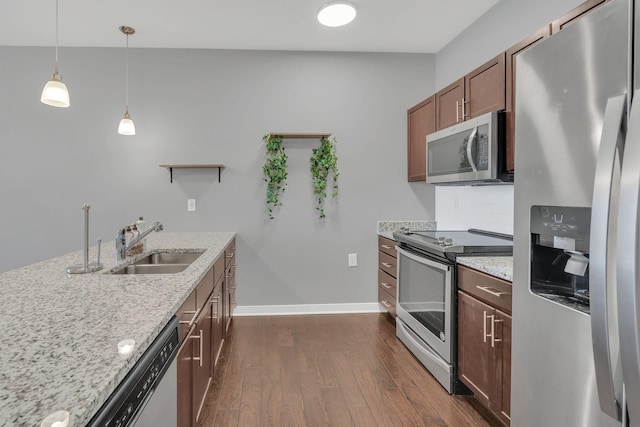 kitchen with dark wood-type flooring, a sink, appliances with stainless steel finishes, light stone countertops, and tasteful backsplash