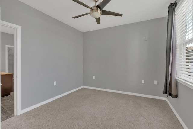 empty room featuring carpet, baseboards, and a ceiling fan