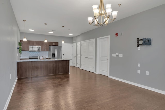 kitchen featuring appliances with stainless steel finishes, dark wood-style flooring, a peninsula, and baseboards