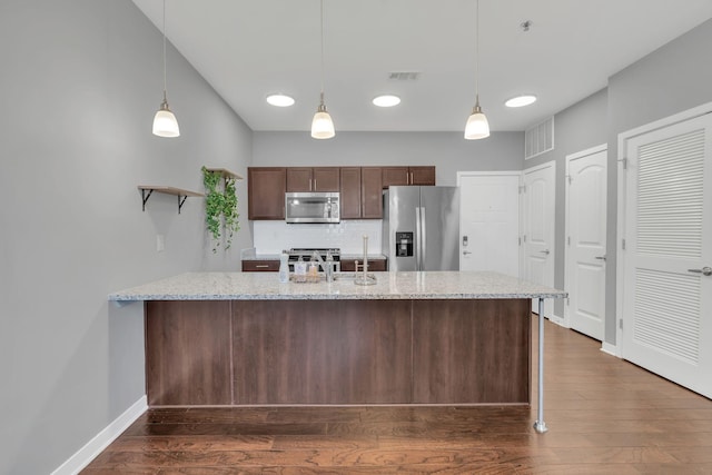 kitchen featuring appliances with stainless steel finishes, dark wood-type flooring, hanging light fixtures, a peninsula, and backsplash