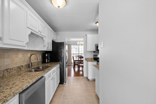 kitchen with appliances with stainless steel finishes, white cabinetry, a sink, and light tile patterned floors