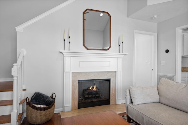 living room featuring baseboards, a premium fireplace, visible vents, and wood finished floors