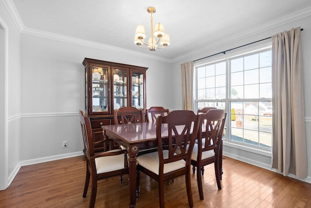 dining area featuring baseboards, crown molding, an inviting chandelier, and wood finished floors