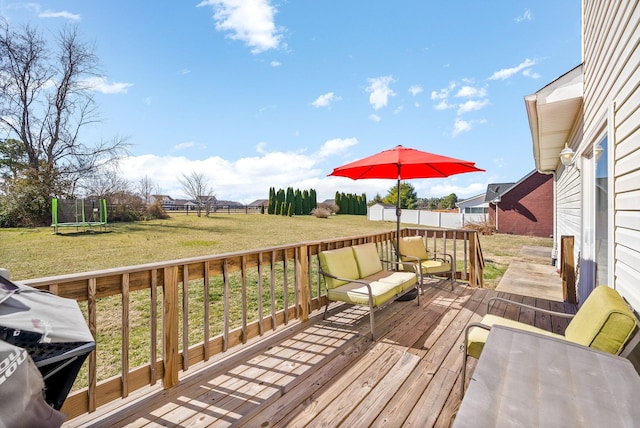 wooden deck featuring a fenced backyard, a trampoline, outdoor lounge area, and a lawn