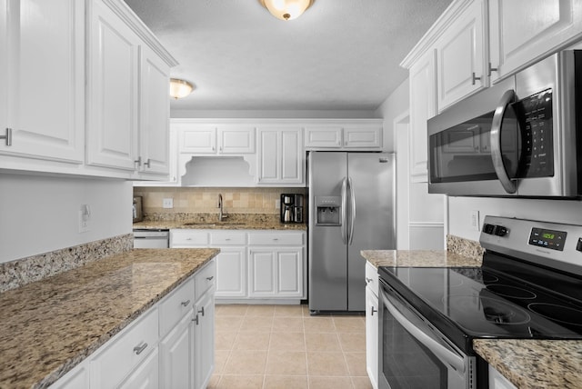 kitchen featuring light tile patterned floors, white cabinets, decorative backsplash, stainless steel appliances, and a sink